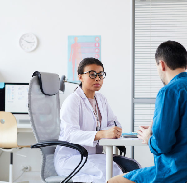 Female doctor discussing with patient his disease while sitting at the table during his visit at the hospital