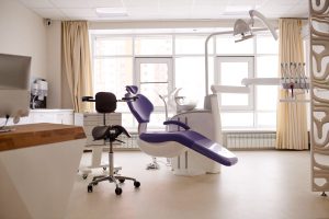 Spacious dental room with panoramic windows: cozy purple chair, modern equipment, no people