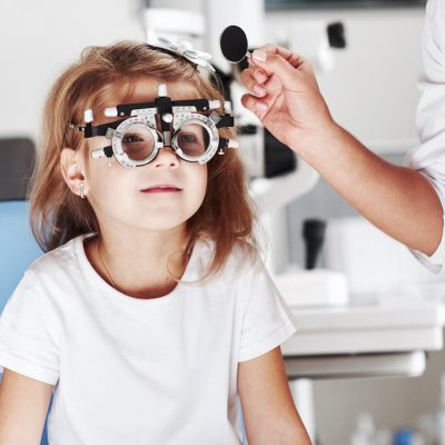 Now I will close one eye. Doctor checking little girl sight and tuning the phoropter.
